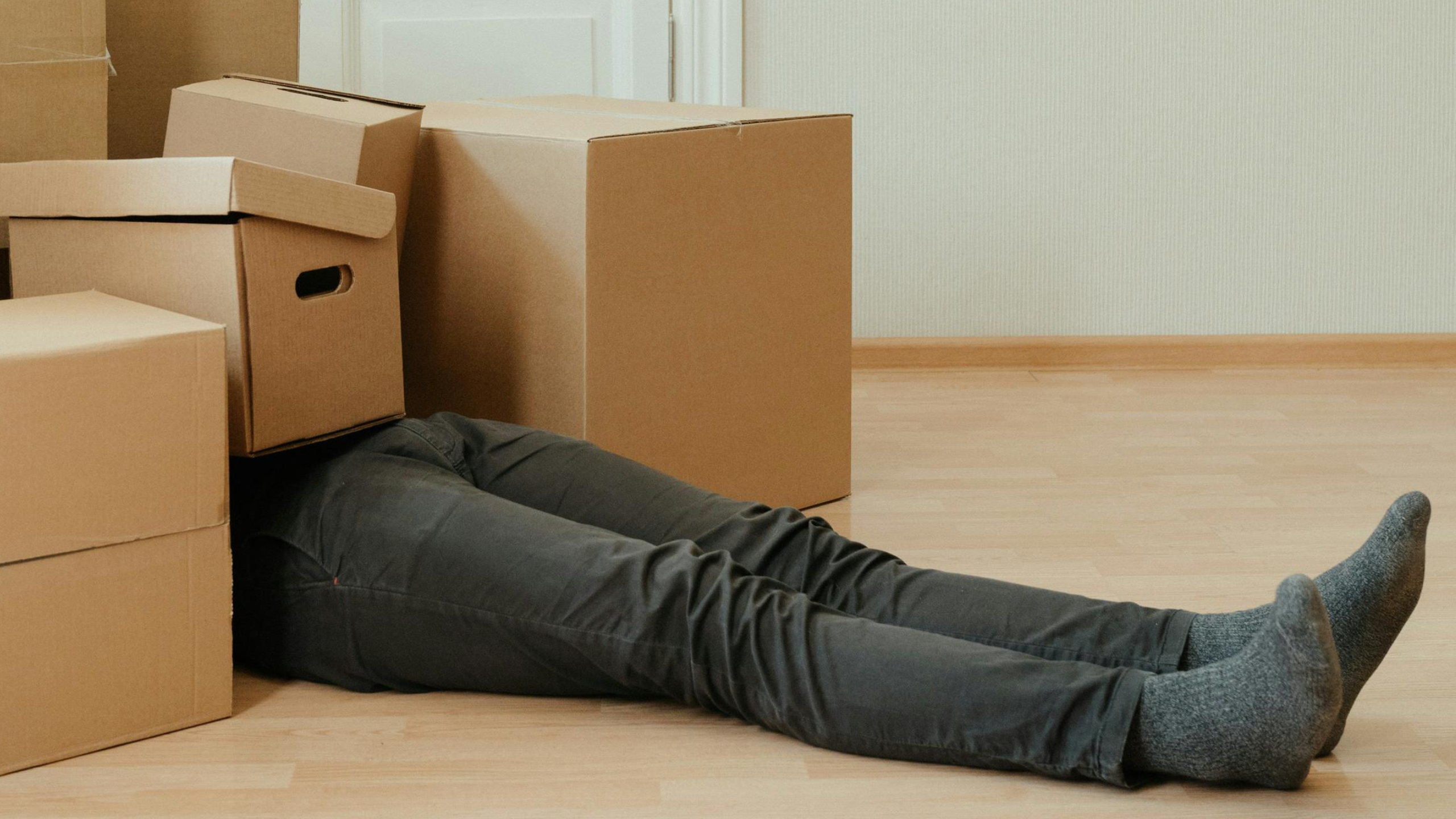 man laying under boxes