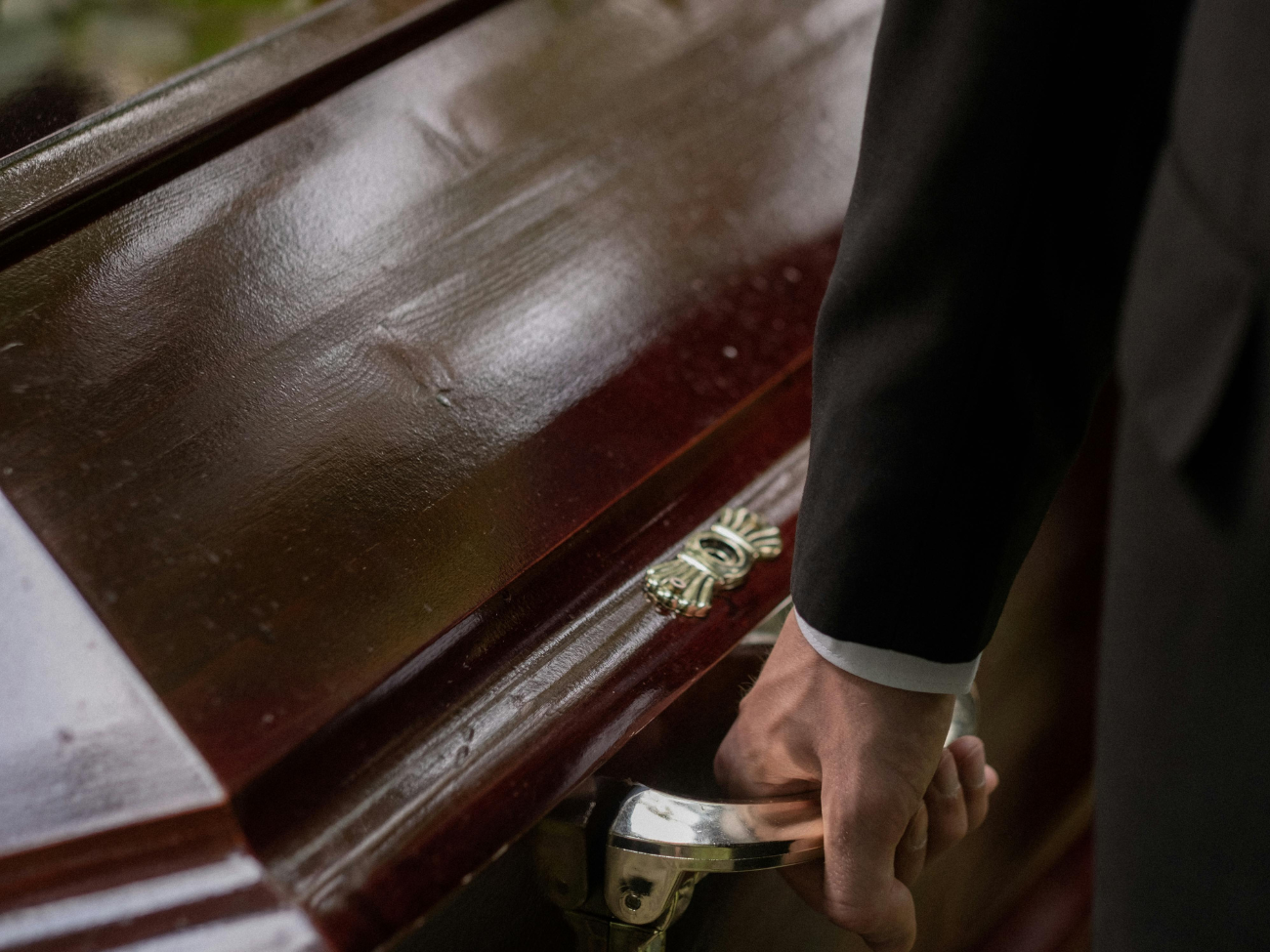 man holding casket after a service in a funeral home
